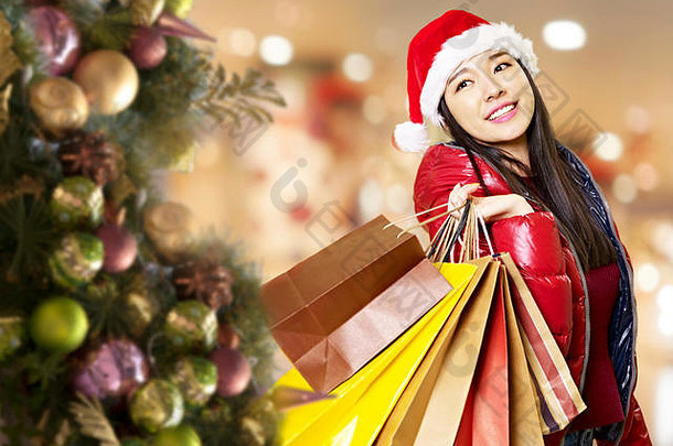 年轻的亚洲女人携带纸袋肩膀圣诞节购物快乐微笑