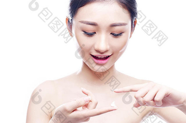 年轻的亚洲女人应用奶油乳液孤立的白色背景