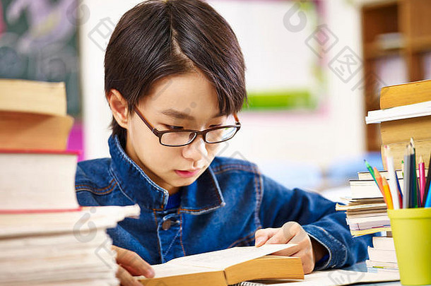 亚洲小学学校男孩穿眼镜阅读厚书