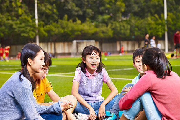 集团亚洲小学学校男孩女孩坐着聊天操场上草