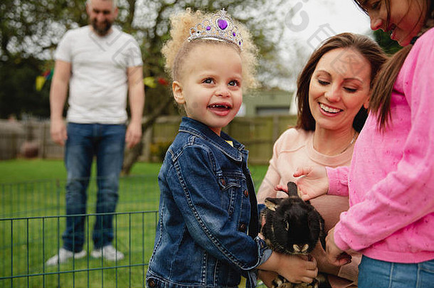 女孩兴奋抚摸宠物兔子ourdoors复活节花园聚会，派对