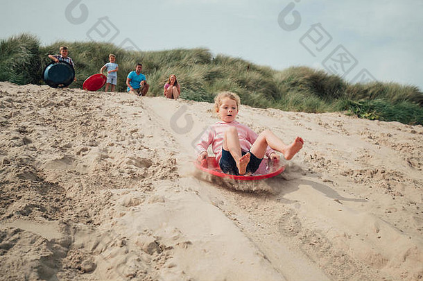 女孩有趣的滑动沙子沙丘家庭等待前