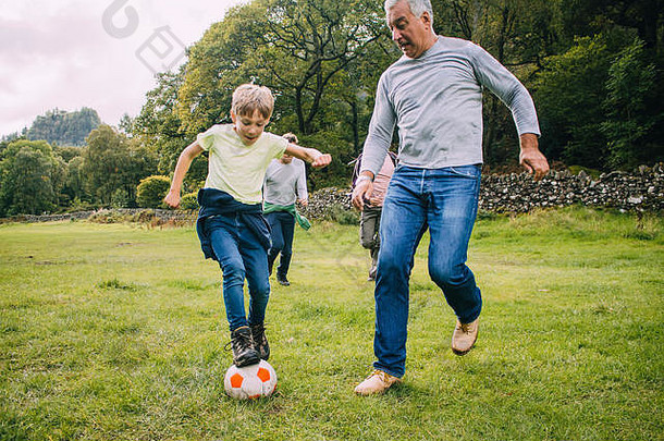 一代家庭玩足球场男孩父亲祖父