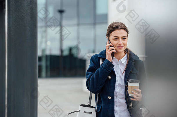 女商人走工作城市持有咖啡杯会说话的电话