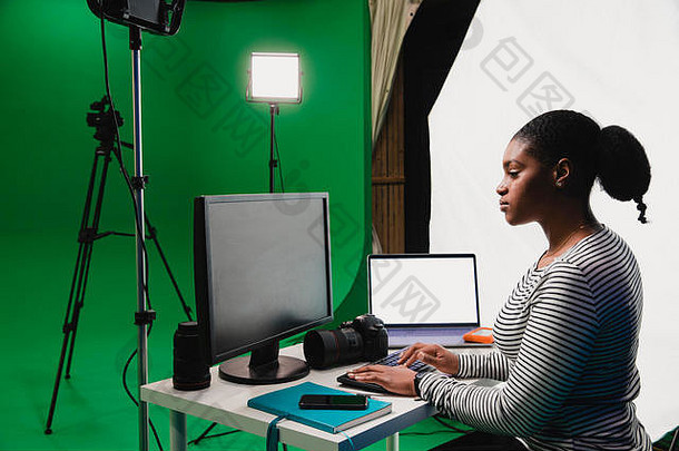 特写镜头侧视拍摄年轻的非洲女人工作桌子上电影工作室电脑移动PC聪明的电话相机