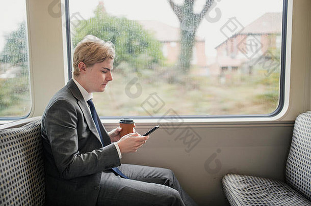 商人早....上下班工作火车年轻的成人聪明的电话持有咖啡坐着