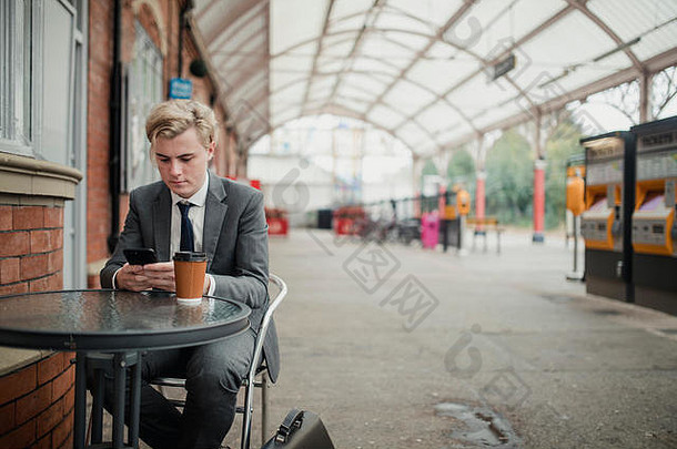 年轻的商人坐着表格火车站聪明的电话杀了时间
