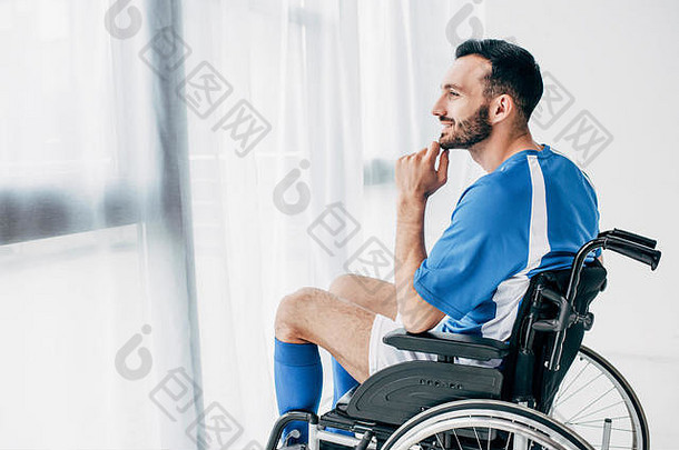 微笑男人。足球统一的坐着轮椅窗口