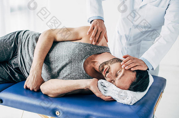 脊椎指压治疗者按摩脖子男人。说谎按摩表格