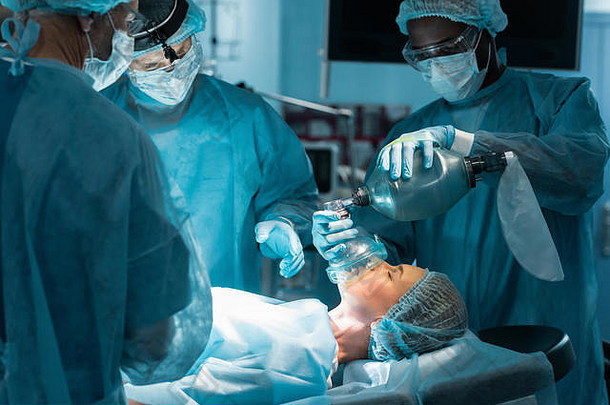 非洲美国麻醉师持有氧气面具病人手术房间