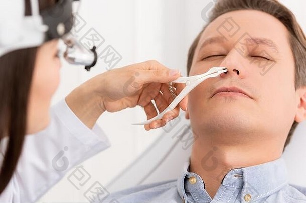 裁剪视图耳鼻喉科专家检查鼻子英俊的男人。鼻窥器