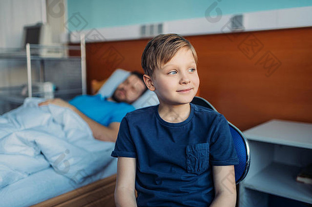 儿子坐着椅子生病的父亲睡觉医院床上病房爸爸儿子