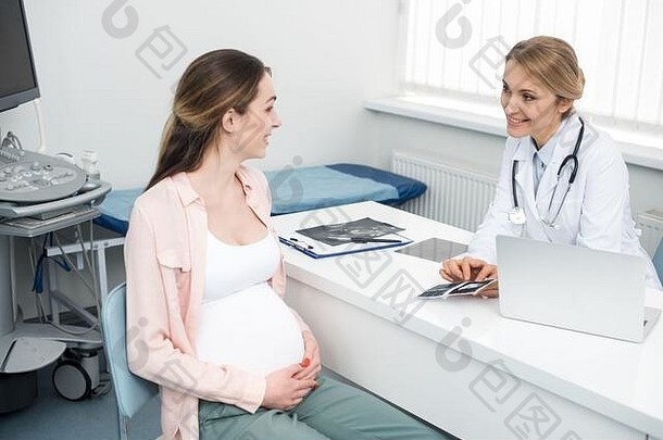 微笑医生显示超声波扫描年轻的怀孕了女人诊所