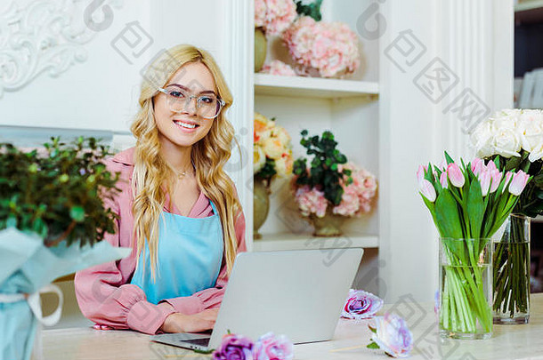 美丽的女花商店老板眼镜坐着桌子上相机移动PC
