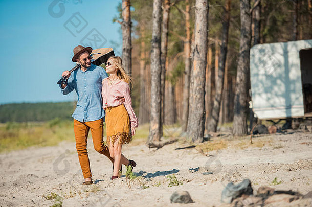美丽的年轻的夫妇拥抱走声吉他森林
