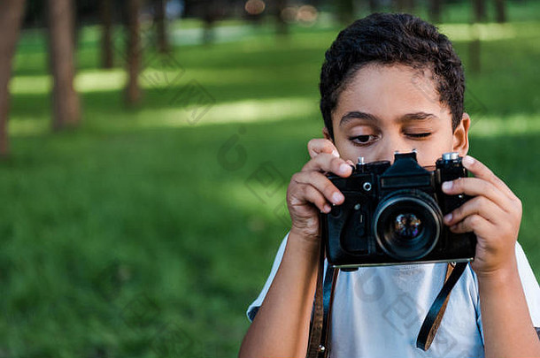 非洲美国男孩持有数字相机会说话的照片公园