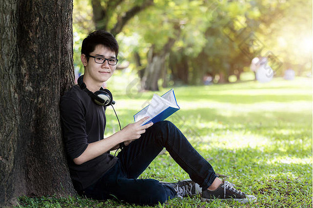 亚洲年轻的英俊的男人。学生阅读书自然学生