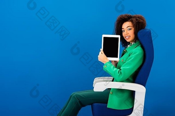 微笑非洲美国女人持有数字平板电脑孤立的蓝色的