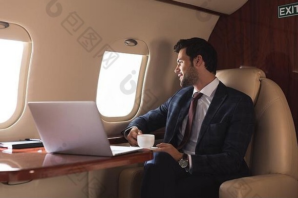 沉思的商人持有杯咖啡飞机移动PC业务旅行