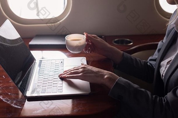 裁剪视图女商人持有咖啡杯工作移动PC飞机业务旅行