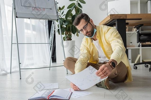深思熟虑的商人纸坐着地板上白板纸上的内容科维德登记