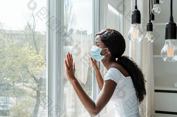 非洲美国女人医疗面具触碰窗户生活房间