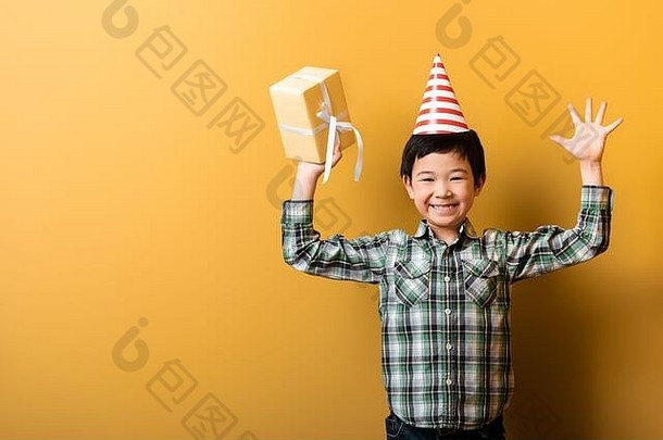 快乐亚洲男孩生日聚会，派对锥持有现在黄色的