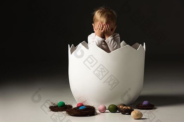 孩子覆盖脸内部蛋壳复活节鸡蛋巢黑色的背景