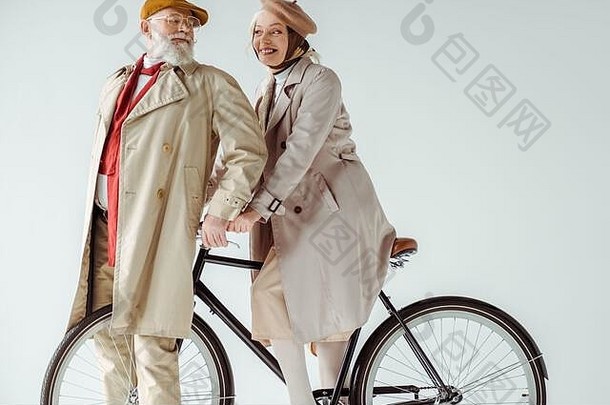 时尚的高级夫妇微笑自行车孤立的白色