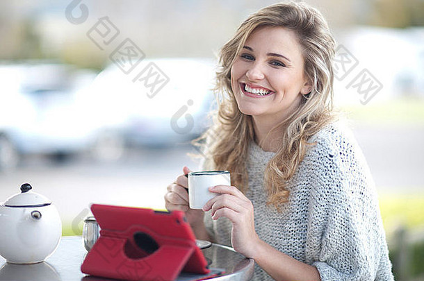 年轻的女人坐着咖啡馆杯咖啡数字平板电脑