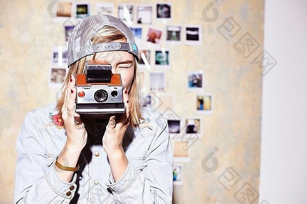 年轻的女人前面照片墙采取照片复古的相机