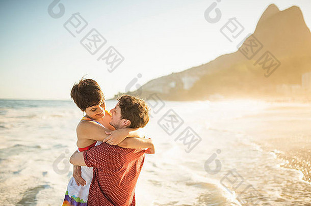 年轻的夫妇拥抱日落伊帕内玛海滩里约巴西