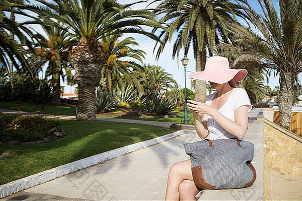 中期成人女人发短信智能手机公园花园海岸