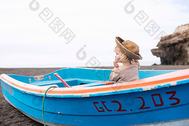 蹒跚学步的女孩坐着船海滩