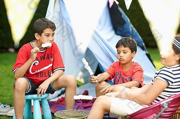 女孩兄弟吃烤棉花糖前面自制的帐篷花园