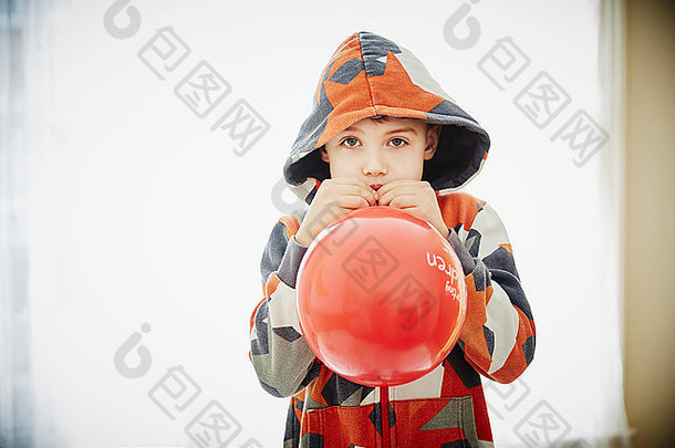 年轻的男孩吹红色的气球
