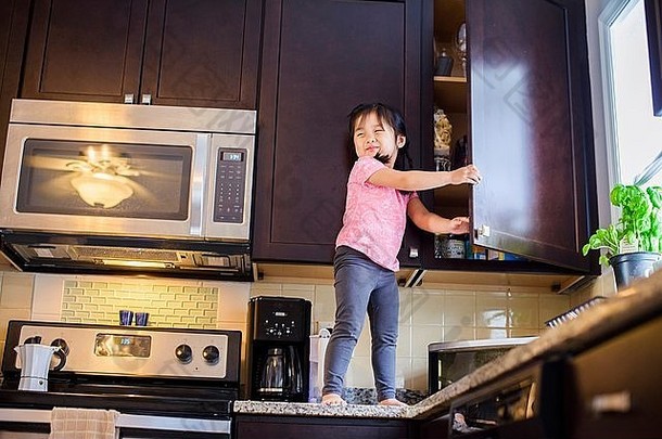 年轻的女孩站厨房工作表面对待橱柜