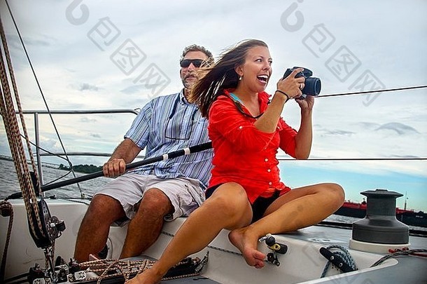 年轻的女人坐着帆船采取照片微笑