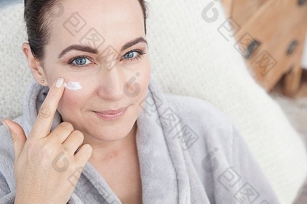 成熟的女人应用保湿霜脸