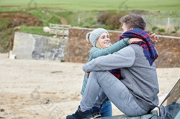 浪漫的年轻的夫妇坐着车罩海滩