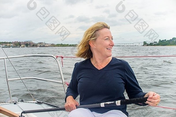 成熟的女人操舵帆船微笑