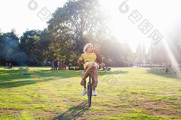 年轻的夫妇有趣的自行车日落聚会，派对公园