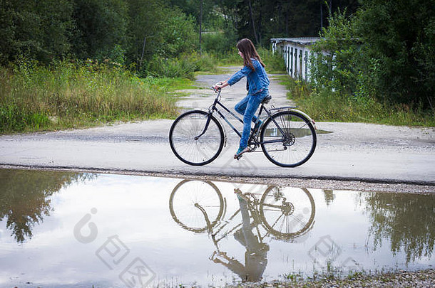 十几岁的女孩骑自行车农村路过去的水坑
