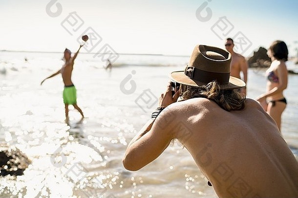 年轻的男人。拍摄朋友玩美国足球海纽波特海滩加州美国