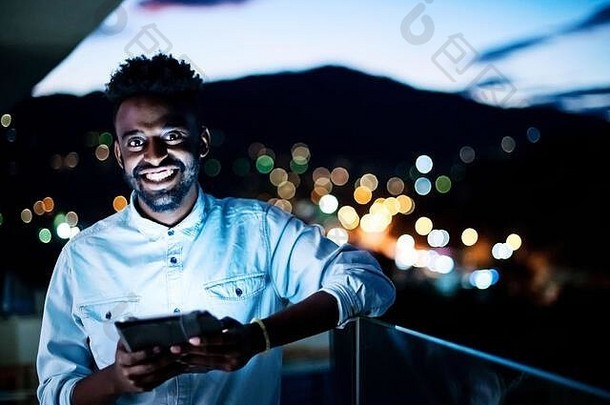 年轻的非洲式发型男人。街晚上平板电脑电脑