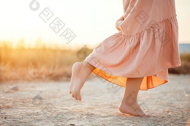 脚女人粉红色的衣服走沙子日落
