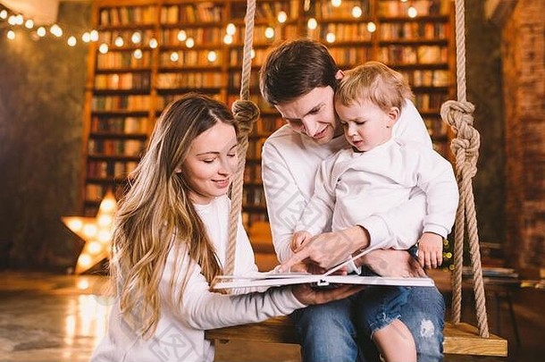 家庭在一起妈妈爸爸儿子阅读故事书坐着摇摆不定的晚上首页家庭为人父母概念