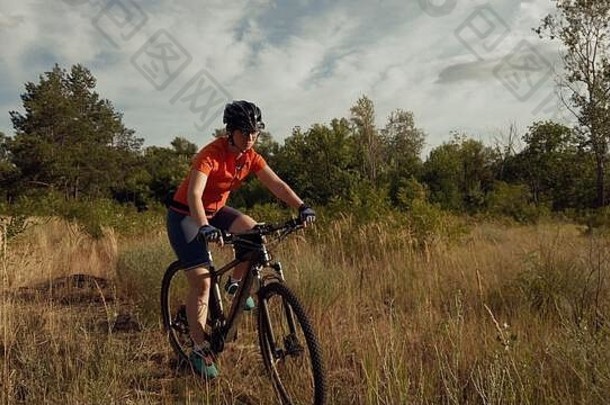 年轻的运动高加索人女人骑山自行车美丽的场羽毛草冒险旅行体育运动自行车