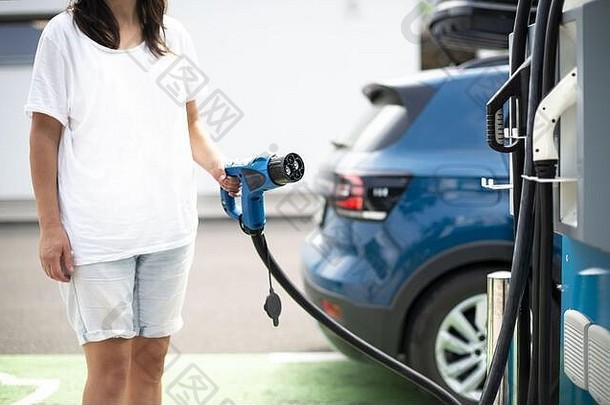 女人负责电车气体站蓝色的车电插头充电