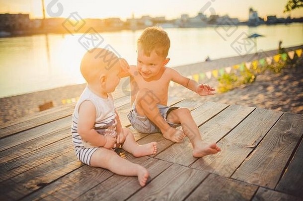男孩坐着码头河银行概念友谊联谊会阳光明媚的快乐的夏天一天孩子们